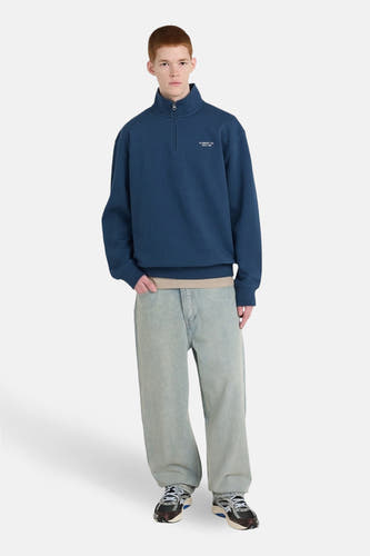 Blauwe sweater van ELEMENT, met korte ritssluiting en losse jeans en sneakers.