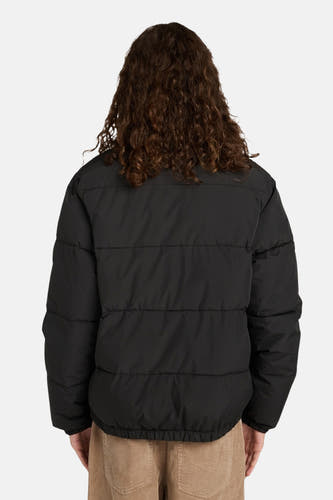Zwarte korte jas van ELEMENT, rugaanzicht, met lange krullende bruine haren en een corduroy broek.