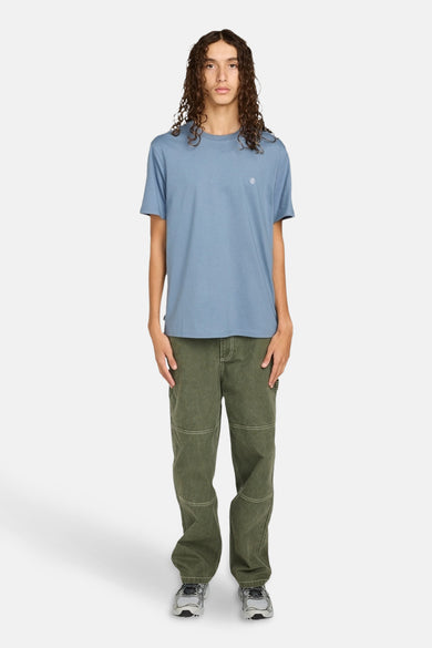 T-shirt bleu à manches courtes d'ELEMENT, avec un petit logo sur la poitrine, associé à des pantalons verts et des baskets.