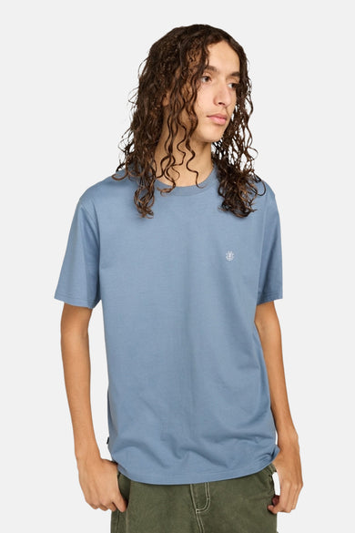 T-shirt bleu à manches courtes d'ELEMENT, porté avec un pantalon vert.