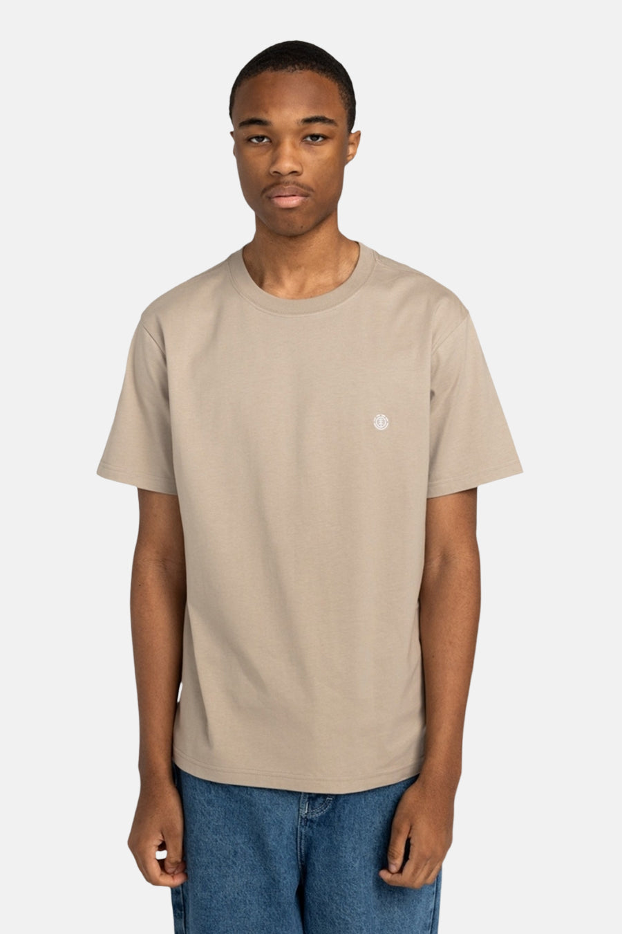 Beige T-shirt met korte mouwen van ELEMENT, met klein logo op de borst en gedragen met een blauwe jeans.