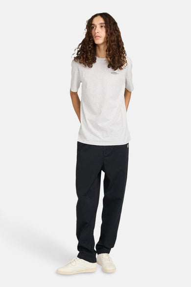 Zwarte chino van ELEMENT, gecombineerd met een lichtgrijs T-shirt en crèmekleurige sneakers.