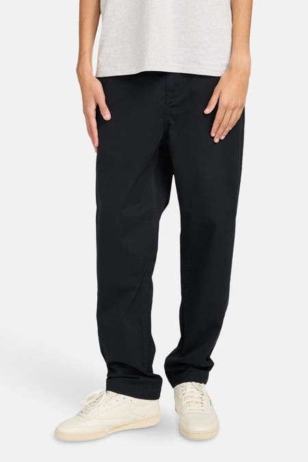 Zwarte chino van ELEMENT, met lichtgekleurde schoenen en een grijs t-shirt.
