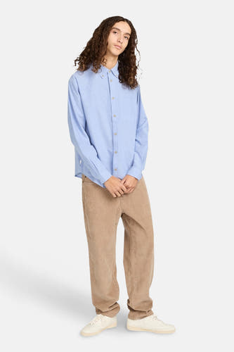 Beige broek van ELEMENT, gecombineerd met een lichtblauw overhemd en witte sneakers.