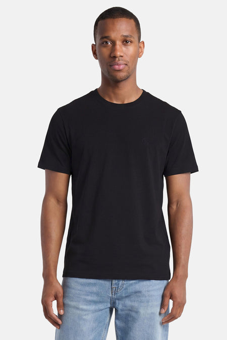 Zwart T-shirt van ELEMENT met ton-sur-ton geborduurd logo op de borst, gedragen door een man in lichtblauwe jeans.