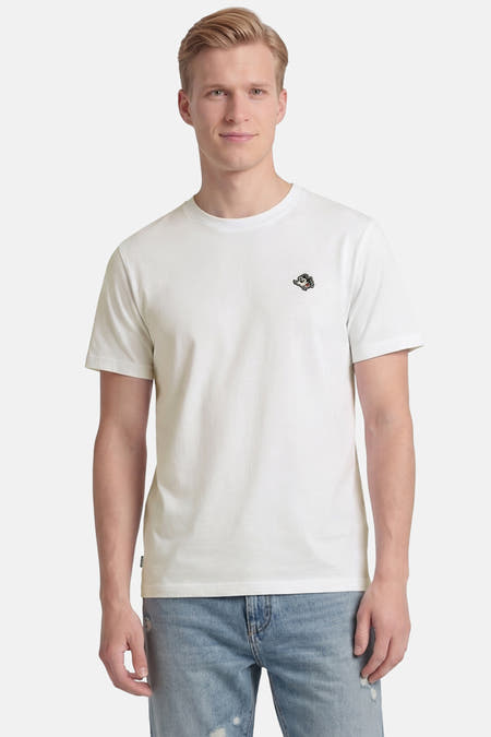 Wit T-shirt van ELEMENT met korte mouwen en geborduurd cartoonlogo op de borst, gedragen door een man in een lichtblauwe ripped jeans.