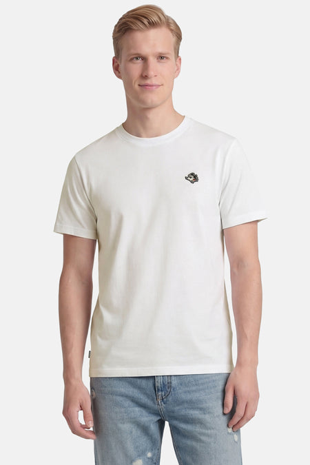 Wit T-shirt van ELEMENT met korte mouwen en geborduurd cartoonlogo op de borst, gedragen door een man in een lichtblauwe ripped jeans.