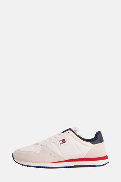 Sneakers blanches de Tommy Jeans avec une couleur bleue marine et un détail rouge sur la semelle, en vue latérale.