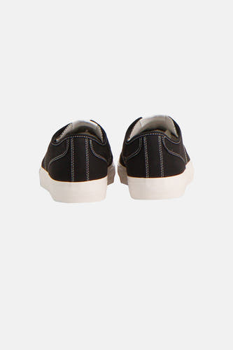 Zwarte sneakers van TOMMY JEANS, met witte zolen en stiksels, gezien van achteren.
