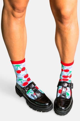 Chaussettes multicolores d'EAT MY SOCKS avec un motif de cerises et une bordure rouge, portées avec des chaussures T-band noires.