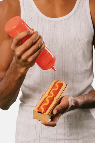 Multikleurige sokken van EAT MY SOCKS, gestyled als hotdogs in een kartonnen bakje met ketchup.
