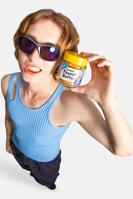 Gele dames sokken van EAT MY SOCKS, lifestyle shot met model in blauw tanktop en zonnebril, houdt pindakaaspot vast