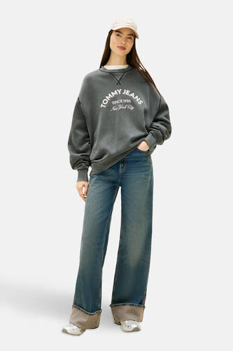 Grijze sneakers van Tommy Jeans, met zilveren details en brede blauwe jeans met omgeslagen pijpen.