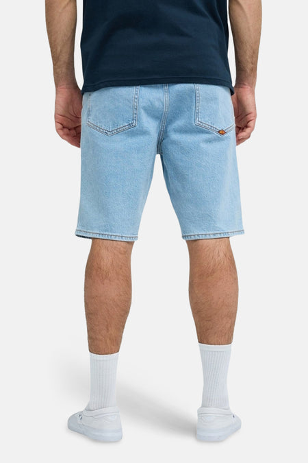 Lichtblauwe jeansshort van Quiksilver, gezien van achteren, met witte sokken en schoenen.
