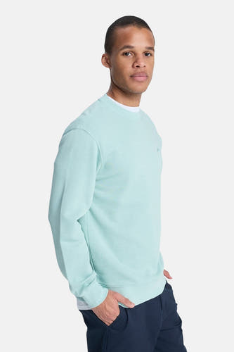 Lichtblauwe sweater van Quiksilver, met lange mouwen en ronde hals, gedragen met een donkerblauwe broek.