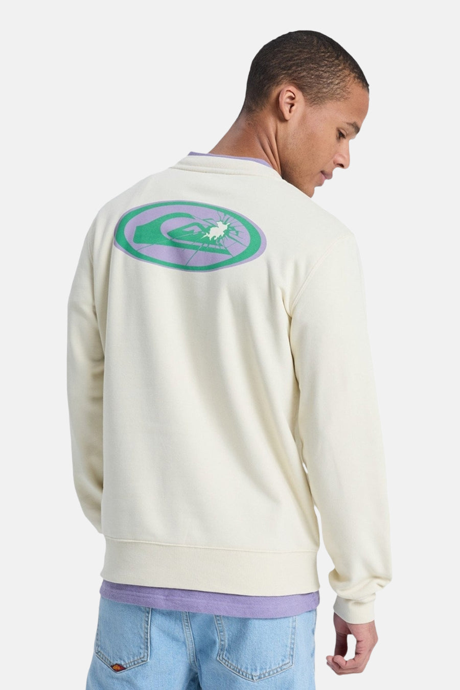 Pull écru Quiksilver, avec un grand imprimé graphique dans le dos et un t-shirt violet en dessous.