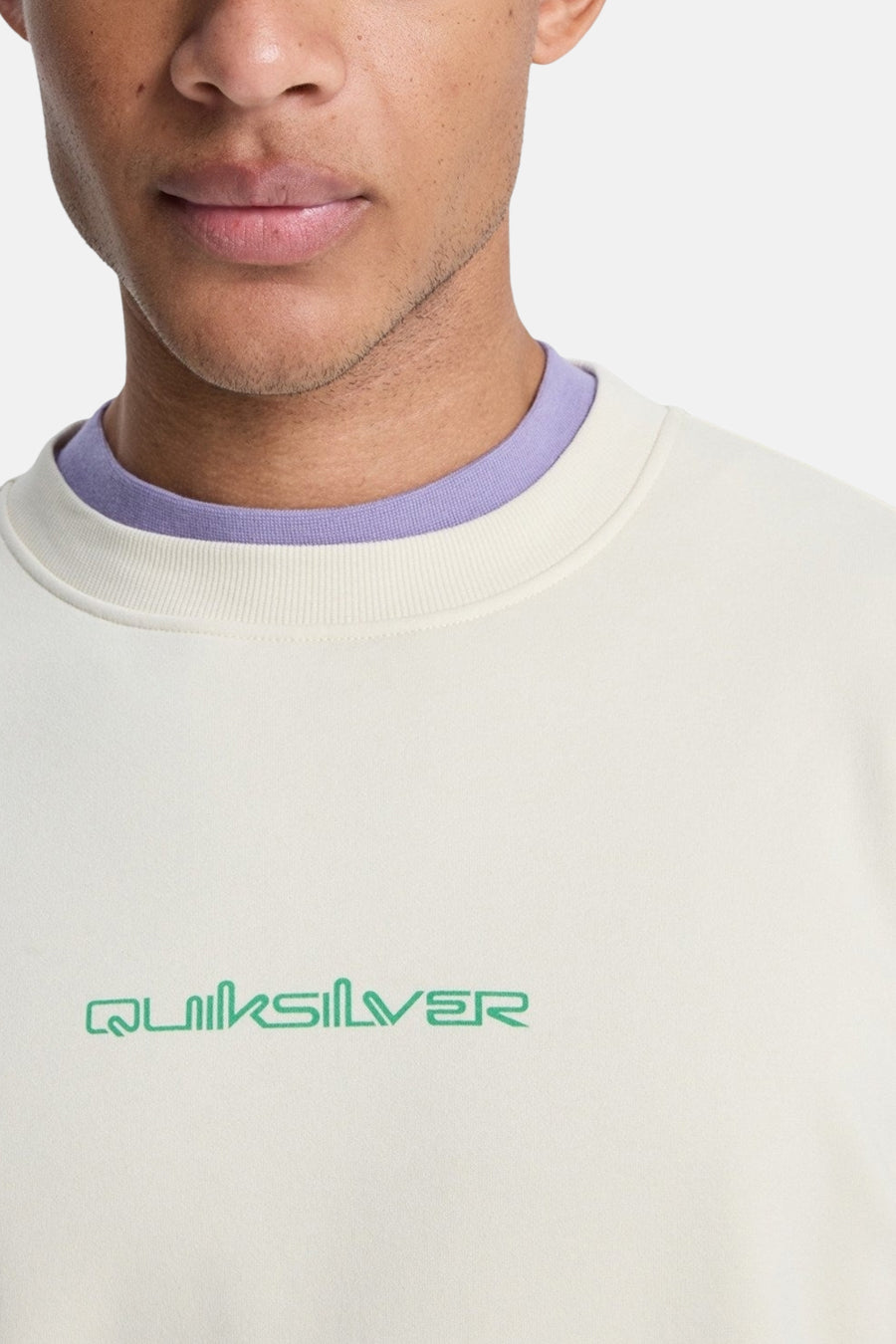 Ecru sweater van Quiksilver, met een paarse kraag en het logo op de borst.
