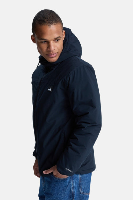 Zwarte korte jas van Quiksilver, met capuchon en blauwe jeans.
