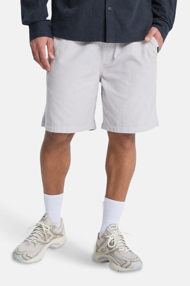 Short gris Quiksilver, avec une fine texture rayée, porté avec des chaussettes blanches et des baskets crème.