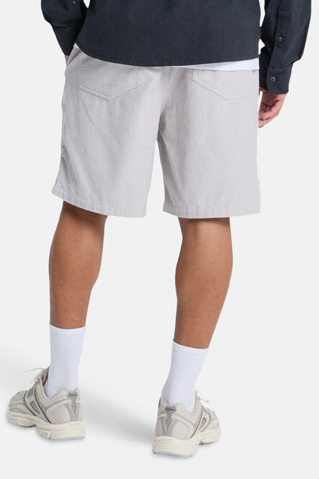 Short gris de Quiksilver, avec texture côtelée verticale, vu de dos, combiné avec des chaussettes blanches et des baskets.