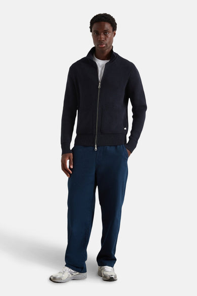 Pantalon bleu de FARAH, associé à un T-shirt blanc et des baskets grises.