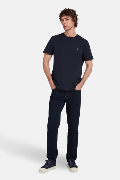 T-shirt bleu à manches courtes de FARAH, porté avec des jeans foncés et des chaussures en toile.
