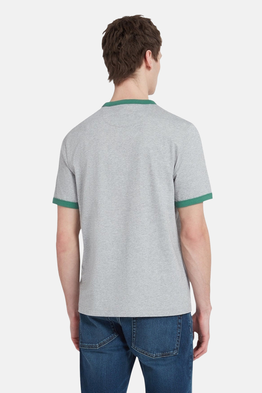 Achterkant van een man in een grijs T-shirt met groene boorden en blauwe jeans.