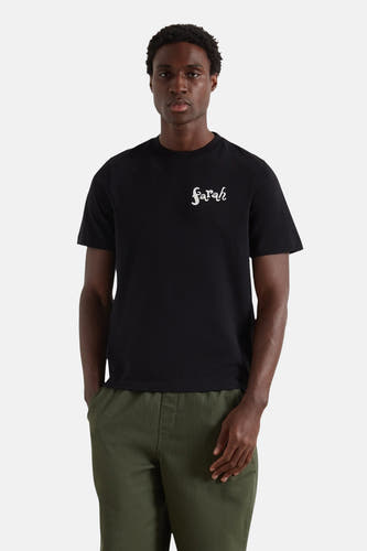 Zwart T-shirt met korte mouwen van Farah, met witte "Sarah" tekst op de borst, gedragen met groene broek.

