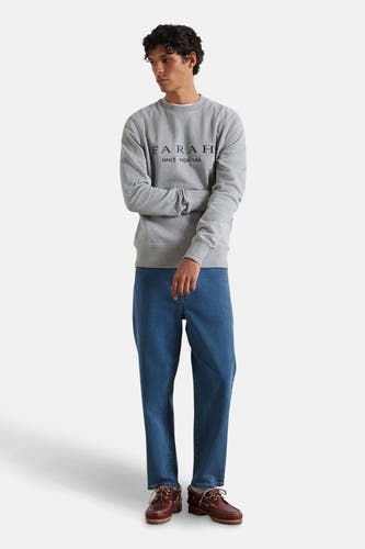 Grijze sweater van FARAH, met lange mouwen, gecombineerd met jeans en bruine boots.
