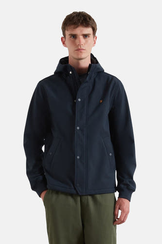 Manteau court bleu de FARAH, avec capuche et fermeture à boutons, porté sur un pantalon vert.