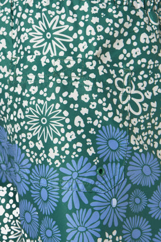 Groene zwemshort van FARAH met een witte bloemenprint en een opgestikte zak met blauwe bloemen.
