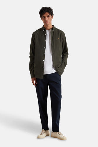 Groen overhemd met lange mouwen van FARAH, gedragen over een wit T-shirt met marineblauwe broek en crèmekleurige sneakers.