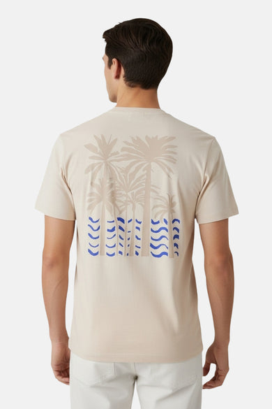 T-shirt beige à manches courtes Guess, avec motif palmier et motifs de vagues bleues au dos.