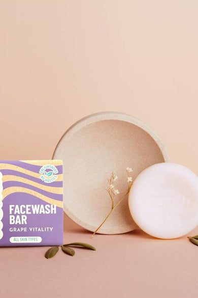 Produit de soin multicolore de WONDR CARE, avec un petit bol beige, du savon blanc et des feuilles décoratives.