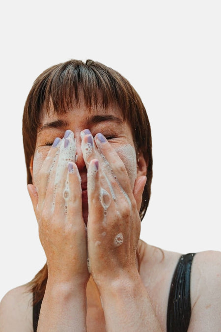 Verzorgingsproduct in het roze van WONDR CARE, een vrouw wast haar gezicht met schuimende zeep.
