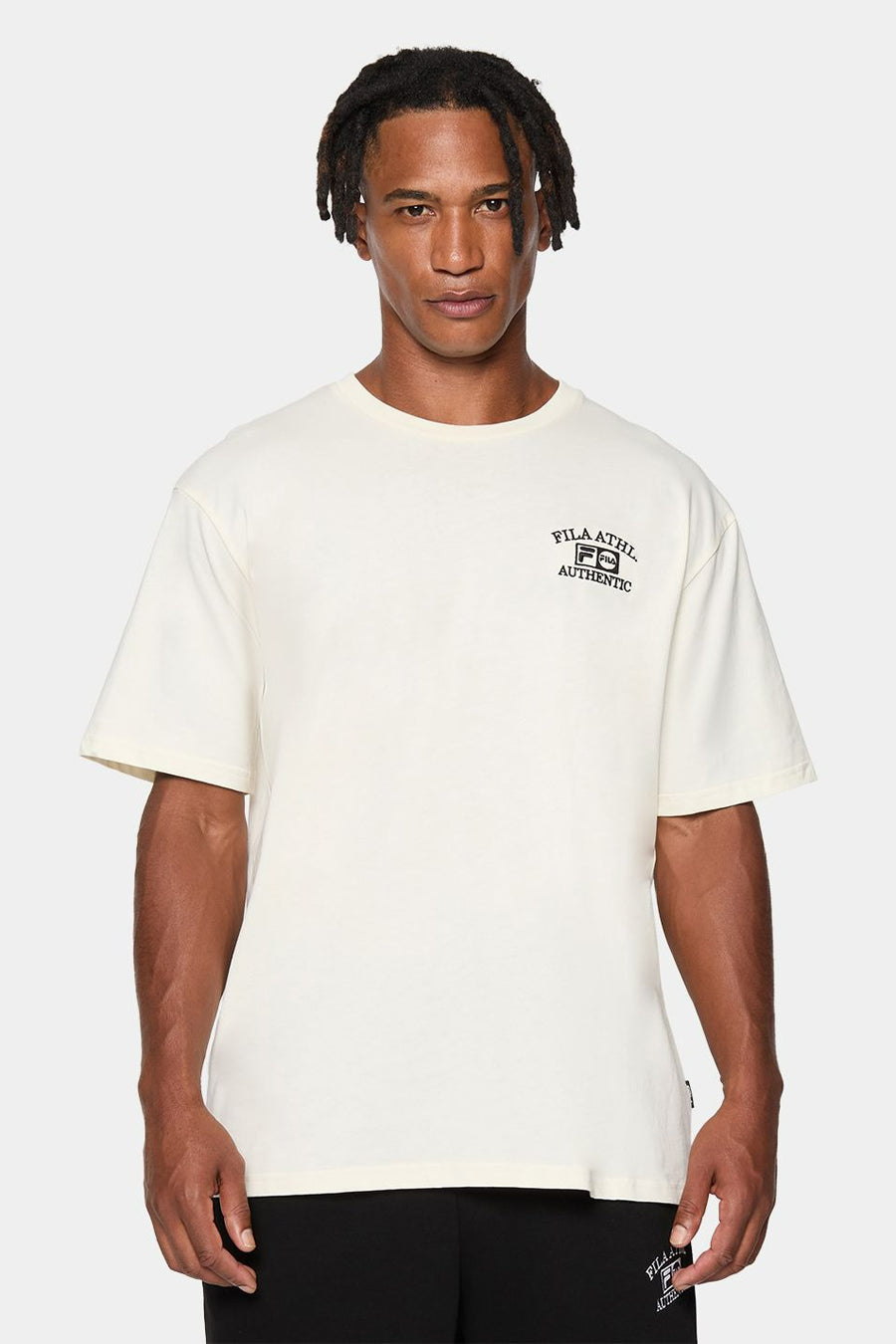 T-shirt écru à manches courtes de FILA, vu de dos, porté avec un pantalon foncé.