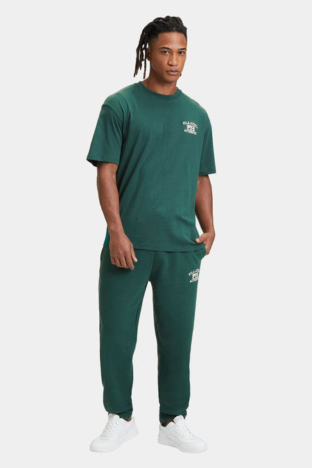 Groen T-shirt met korte mouwen van FILA, met logo op de borst, gecombineerd met groene joggingbroek en witte sneakers.