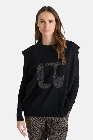 Mouwloze zwarte top van LE TEMPS DES CERISES met decoratieve letters voorop, gecombineerd met een broek met panterprint.
