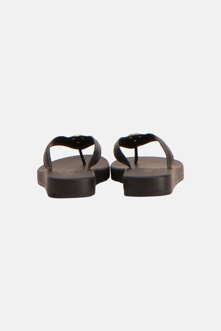 Zwarte slippers van Guess met een goudkleurig detail op de band, van achteren gezien.