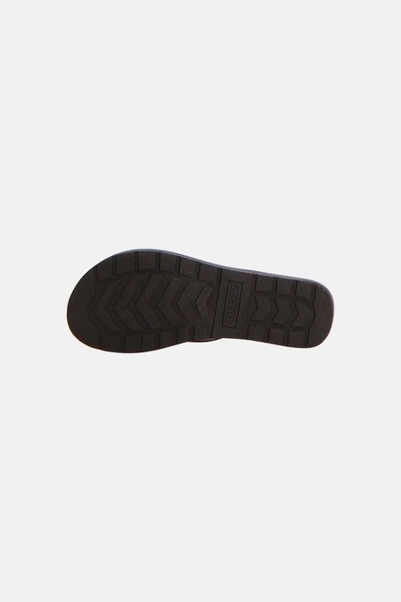 Zwarte slippers van Guess met grove geprofileerde zool en verticaal Guess logo.