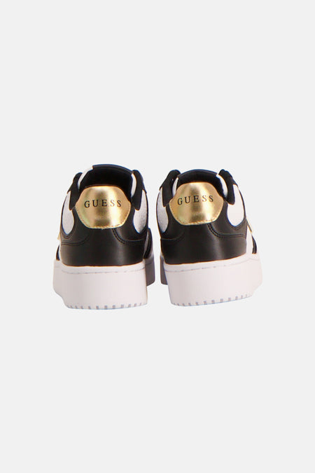 Zwart-witte sneakers van Guess met gouden logo op de hiel, achteraanzicht.