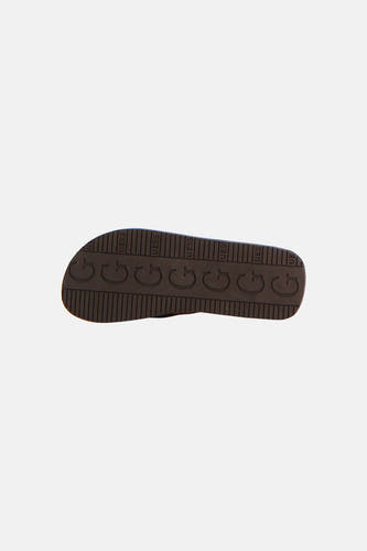 Bruine slipper van Guess, onderkant zichtbaar met herhalende 'G' en 'UESS' logo's.