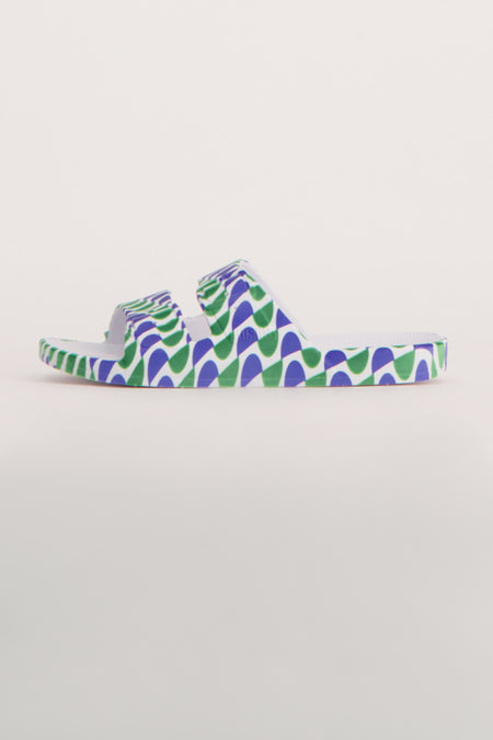 Chaussons bleus de FREEDOM MOSES avec un motif vert et ondulé sur un fond blanc.