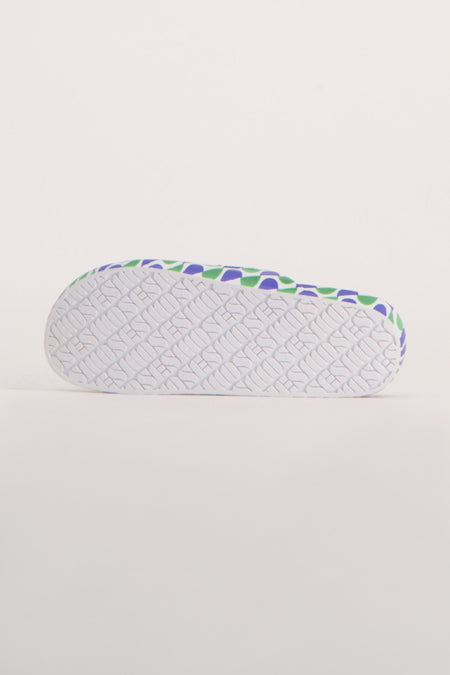 Chaussons bleus de FREEDOM MOSES avec un motif vert et une semelle blanche.