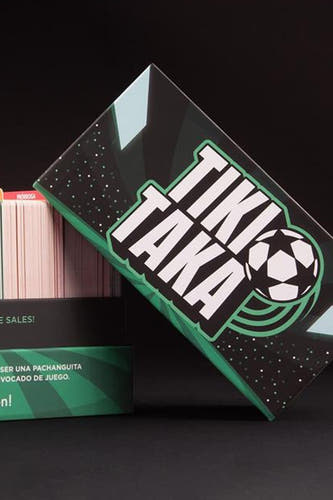 Meerkleurig spel TIKI TAKA van HELLOFUN, met de doos schuin staand en kaarten op de achtergrond.