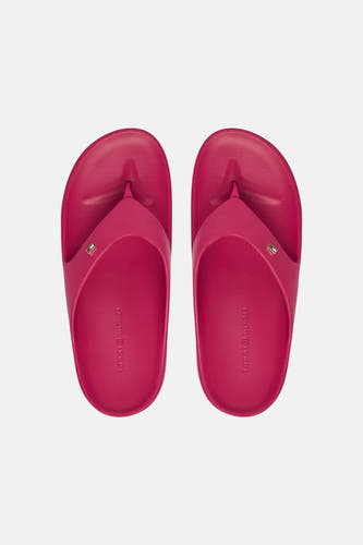 Roze slippers van TOMMY JEANS met een klein logo op de band en merknaam in reliëf op de binnenzool, van bovenaf gezien.