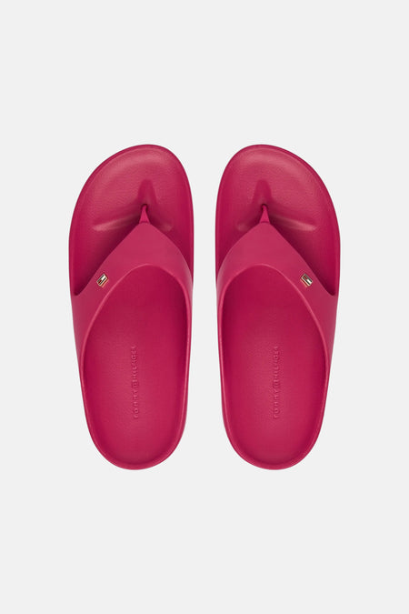Tongs roses TOMMY JEANS avec un petit logo sur la bride et le nom de la marque en relief sur la semelle intérieure, vus de dessus.