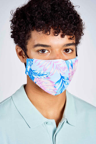 Masque buccal bleu HAILYS avec un imprimé de feuilles en rose et bleu, porté par une personne avec une polo bleue claire.