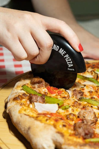 Coupe-pizza noir de Fisura, utilisé pour couper une pizza avec du jambon, du poivron et du fromage.
