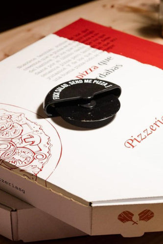 Zwarte pizzasnijder met de tekst "FUCK SALAD, SEND ME PIZZA" op een witte pizzadoos.